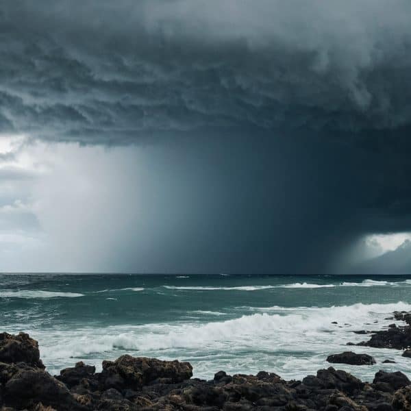 Storm clouds over the ocean with heavy rain in the distance.