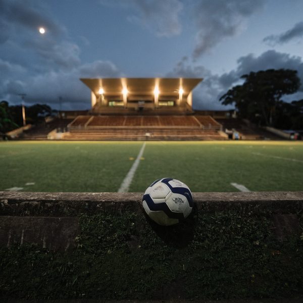 Soccer ball on field at Fiji stadium during evening with cloudy sky.