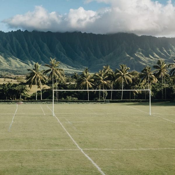 Scenic Fiji soccer field with lush mountains and palm trees in the background.