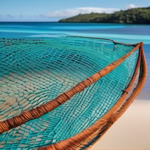 Fishing net on sandy beach with clear blue ocean and distant island.