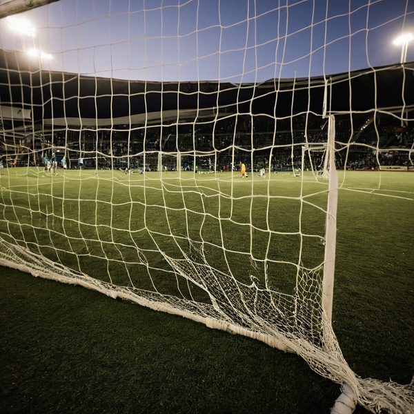 View of a soccer goal on a stadium field during evening hours.