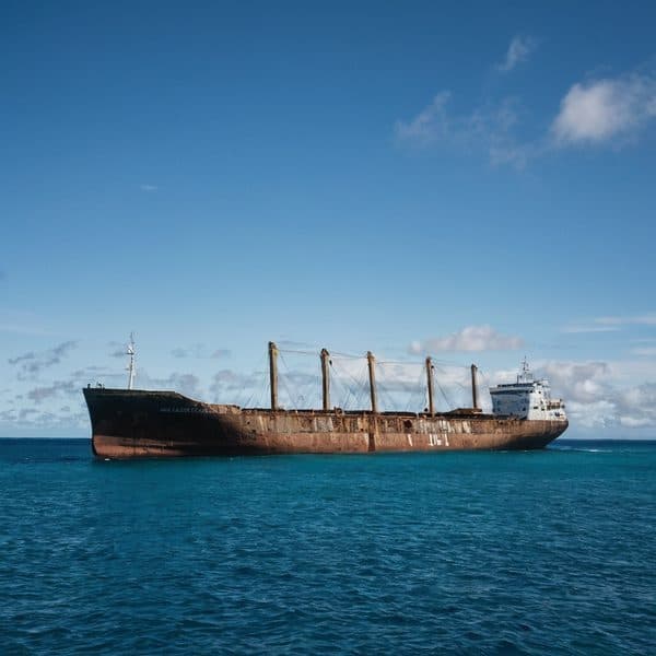 Cargo ship sailing in open ocean under a partly cloudy sky.